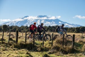 Three cyclists biking the Ohakune Old Coast Road with striking mountain in background