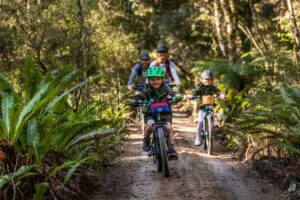 A couple with their two young children riding on their bicycles on the the area mangawhero trail