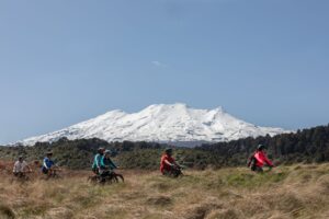 Group of friends riding on the the art mangawhero trail with striking snow covered mountain in the background